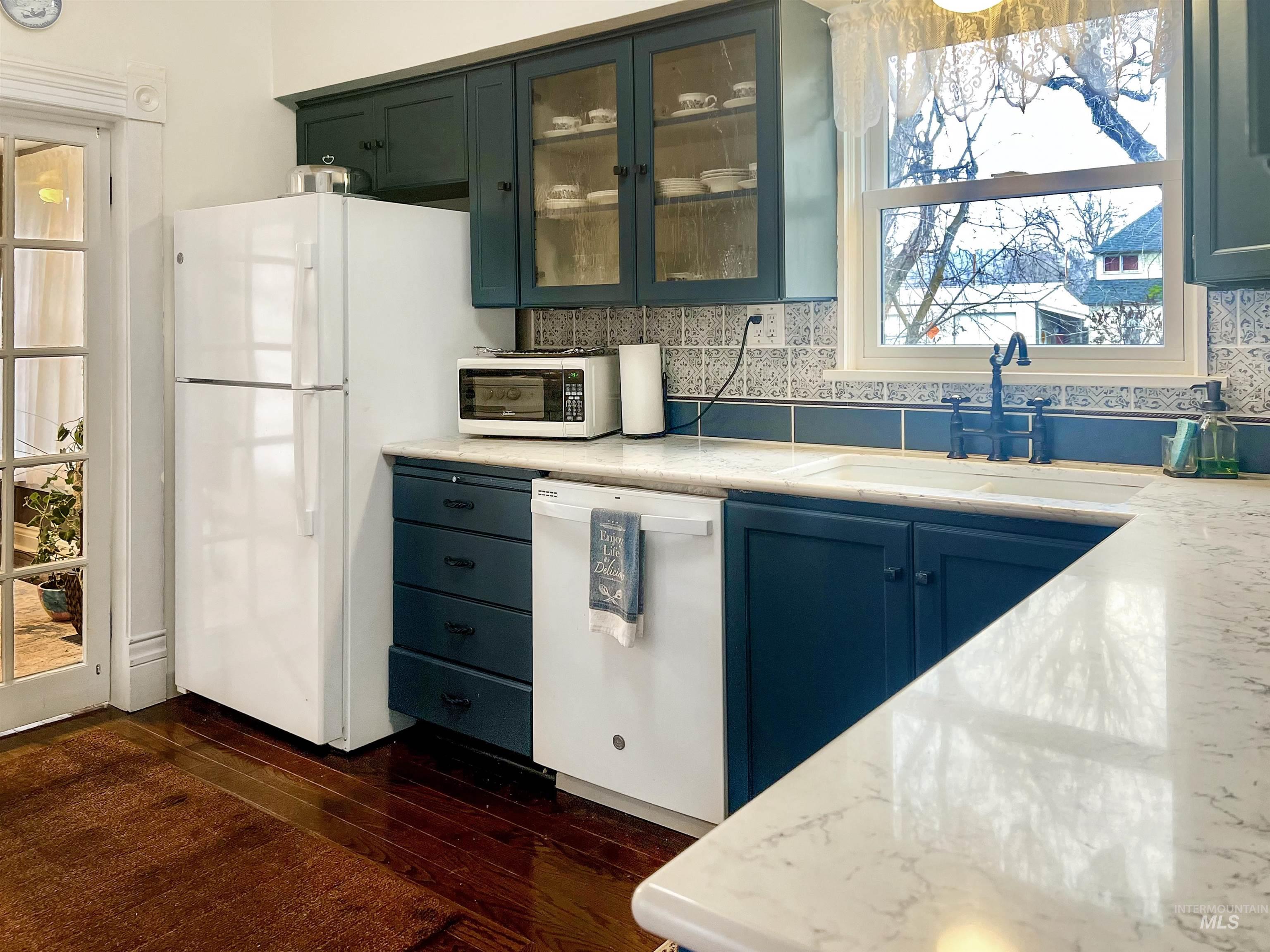 516 East Main Street Weiser, ID 83672 - Photo 18 of 50 Kitchen featuring glass insert cabinets, decorative backsplash, white appliances, and dark wood finished floors