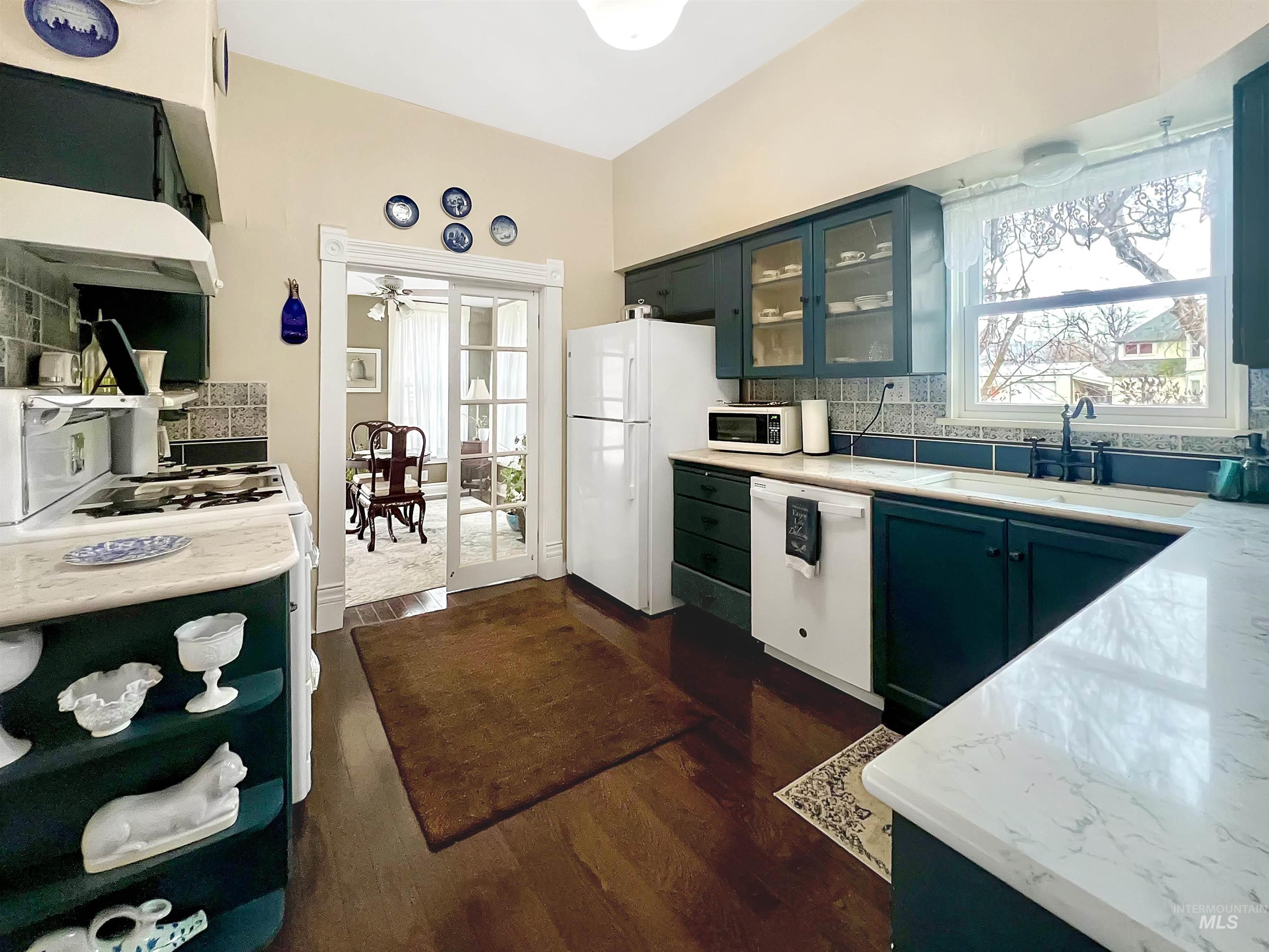 516 East Main Street Weiser, ID 83672 - Photo 19 of 50 Kitchen with glass fronted cabinets, backsplash, white appliances, and dark wood-type flooring