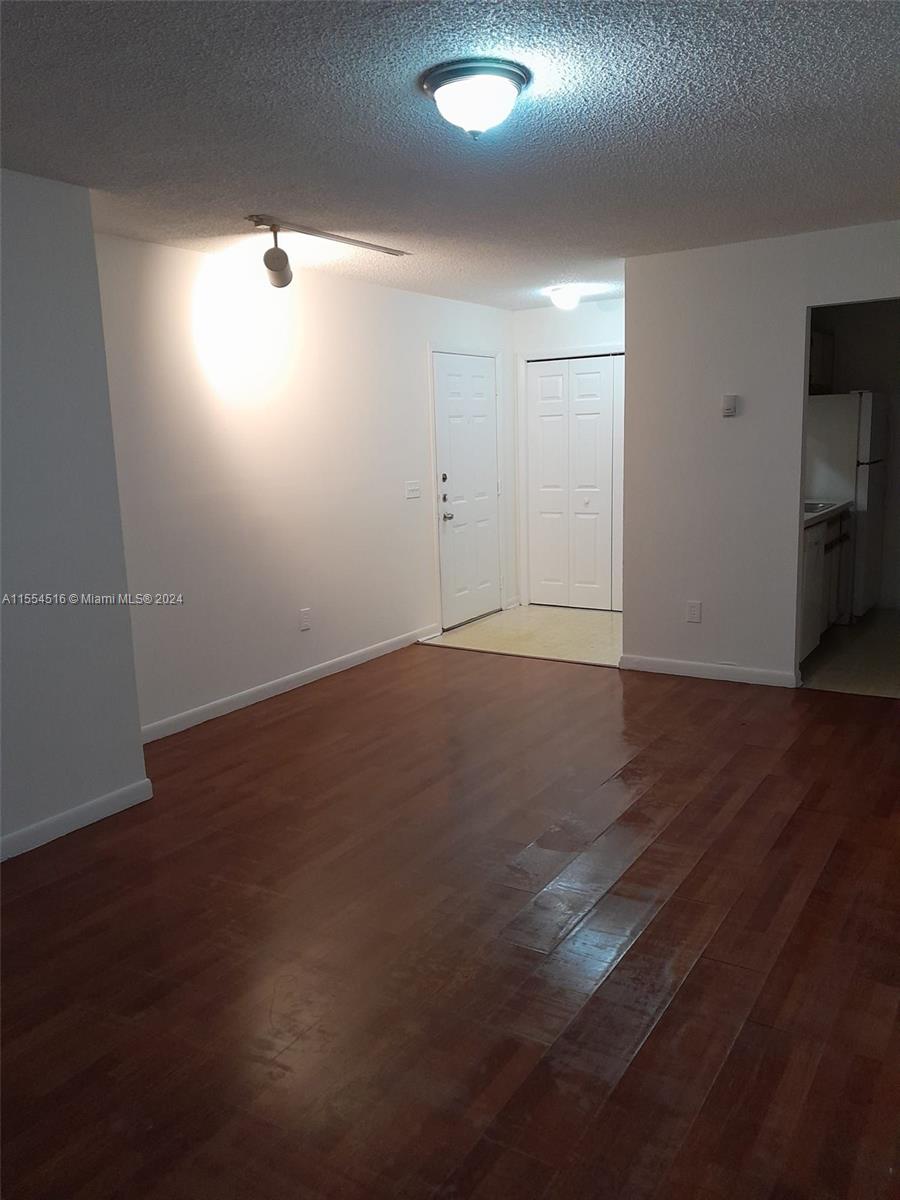 4241 West McNab Road, Unit 27 Pompano Beach, FL 33069 - Photo 3 of 29 an empty room with wooden floor and windows