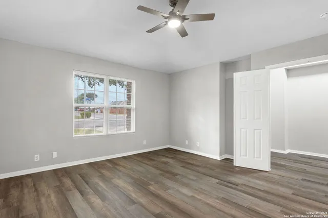 a view of an empty room with wooden floor and a window