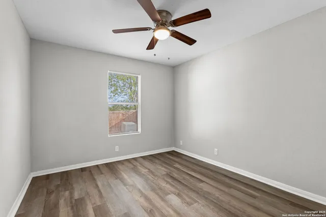 an empty room with a window and a ceiling fan