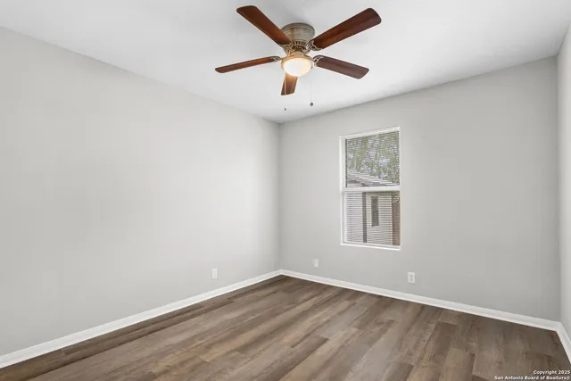 an empty room with a window and a ceiling fan