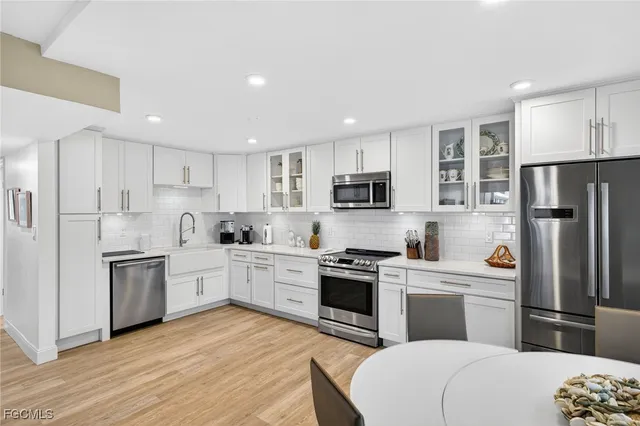 a kitchen with white cabinets stainless steel appliances and a refrigerator