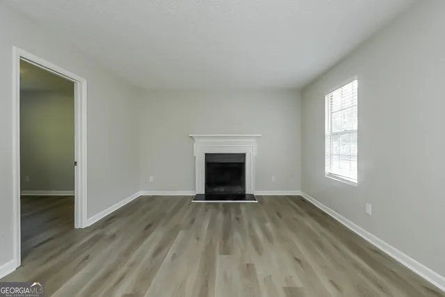 an empty room with wooden floor a fireplace and windows