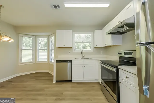 a kitchen with a sink cabinets stainless steel appliances and a window