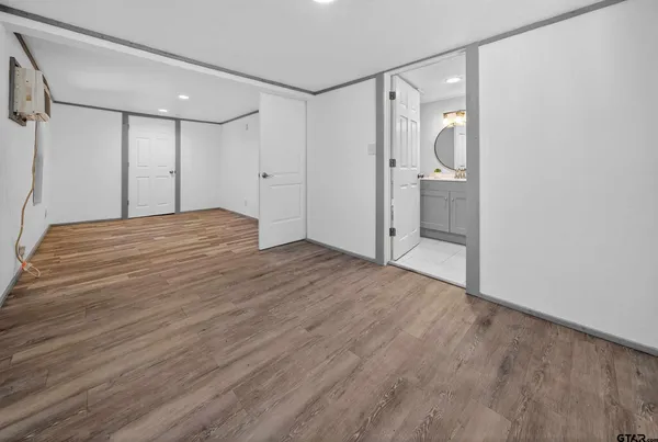 a view of empty room with wooden floor and mirror