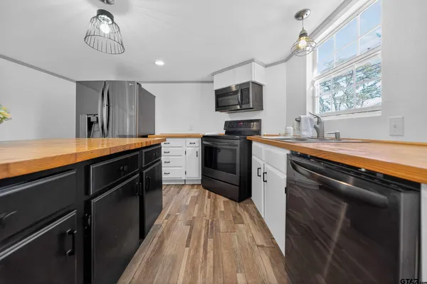 a kitchen with stainless steel appliances granite countertop a sink dishwasher a stove and a refrigerator with wooden floor