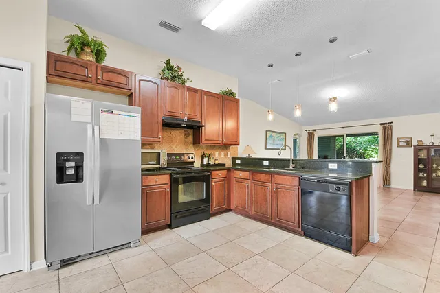 a kitchen with stainless steel appliances granite countertop a refrigerator a stove and a sink
