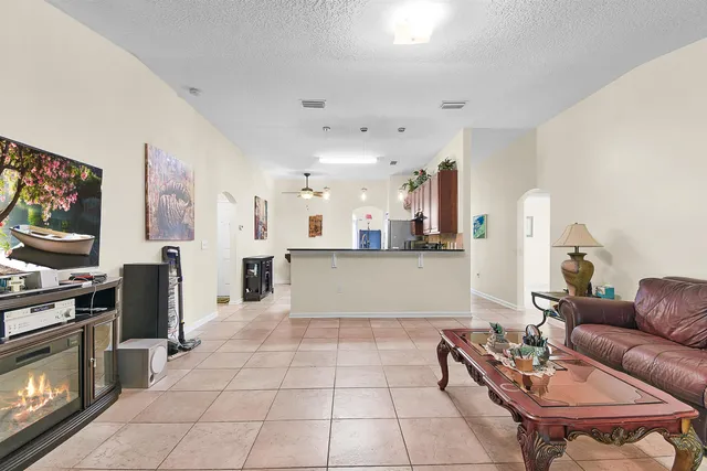 a living room with stainless steel appliances furniture a rug and a kitchen view