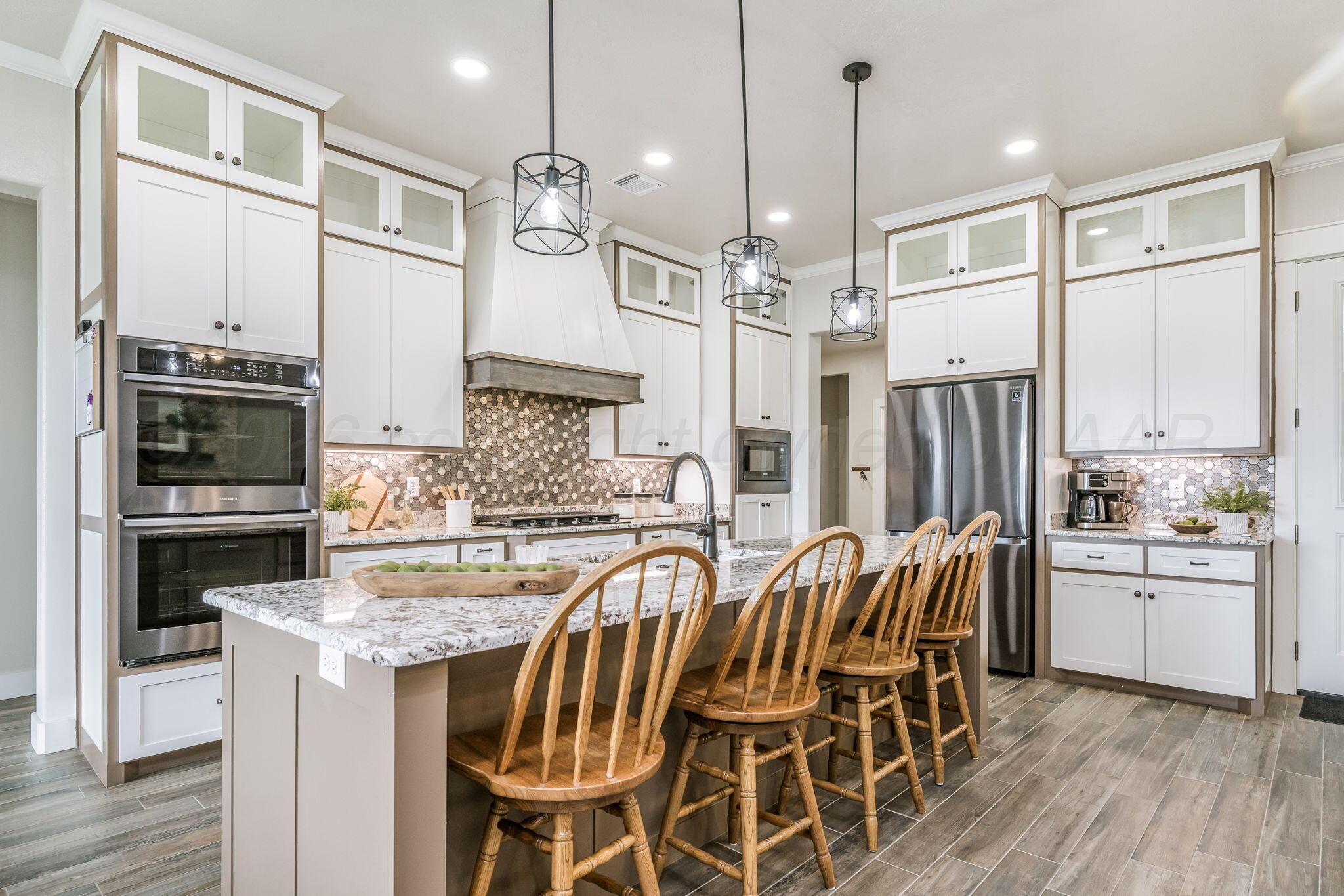 26150 Newton Road Canyon, TX 79015 - Photo 6 of 43 a kitchen with stainless steel appliances kitchen island granite countertop a table chairs and a refrigerator