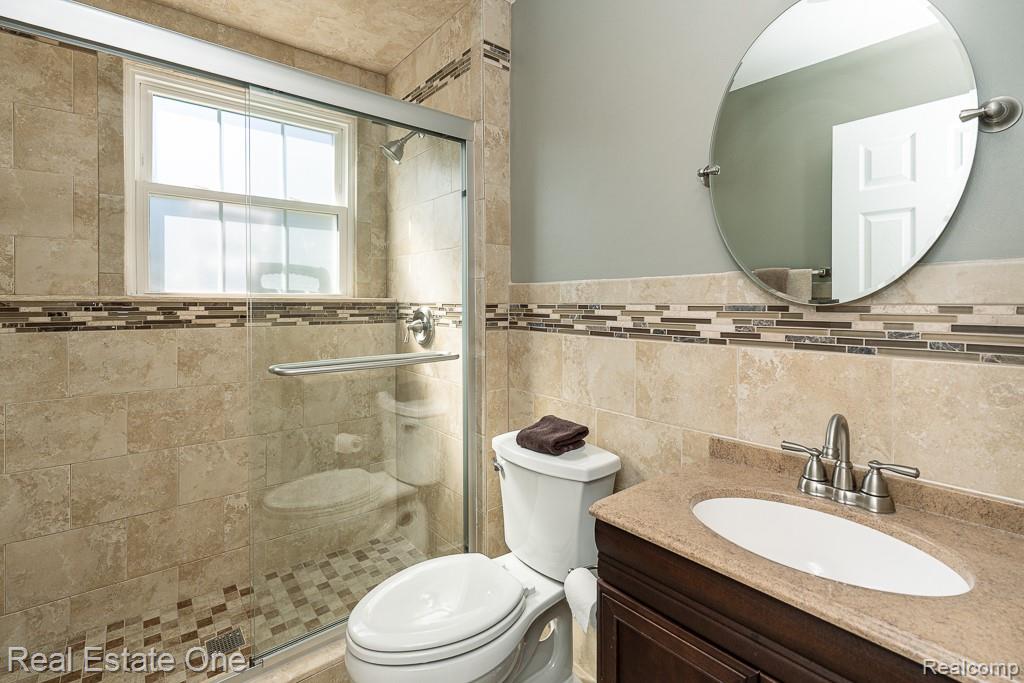 1841 Fair Oak Court Rochester, MI 48309 - Photo 27 of 36 Bathroom featuring vanity, a shower stall, tile walls, and a wainscoted wall