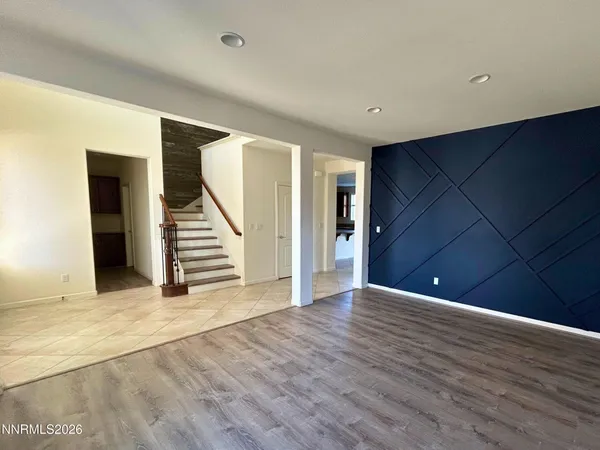 a view of an empty room with wooden floor and stairs