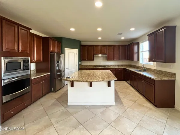 a kitchen with kitchen island granite countertop wooden cabinets a refrigerator and a sink