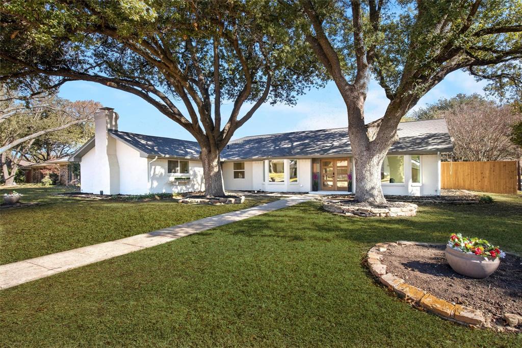 a front view of a house with a garden and trees