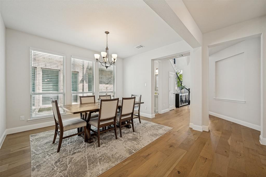 8440 Colburn The Colony, TX 75056 - Photo 6 of 34 Elegant formal dining room featuring an upgraded light fixture, wide plank wood floors, and large windows that fill the space with abundant natural light.