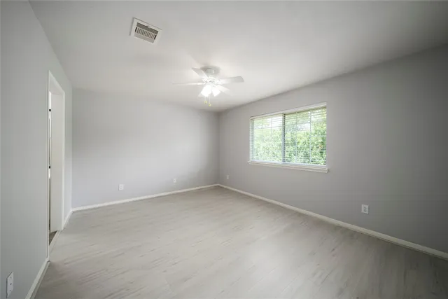 an empty room with a window and a fan