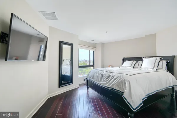 a bedroom with a large bed and a large mirror next to a window