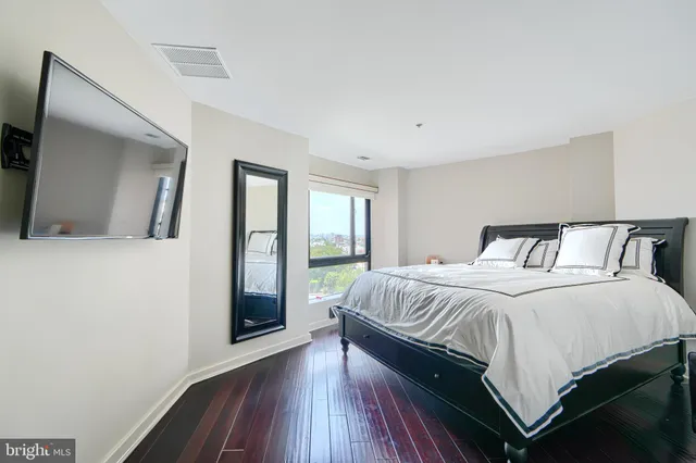 a bedroom with a large bed and a large mirror next to a window