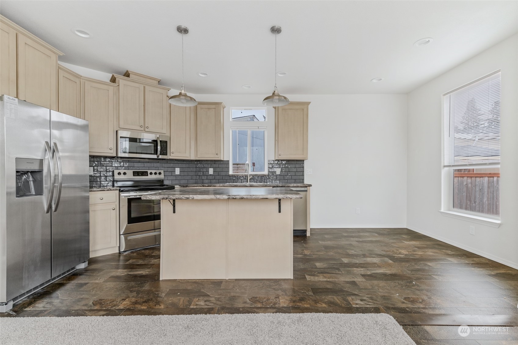 9811 Southwest Herman Road, Unit 45 Tualatin, OR 97062 - Photo 6 of 28 a kitchen with kitchen island granite countertop a stove a sink and white cabinets