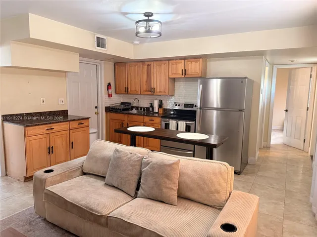 a kitchen with stainless steel appliances a refrigerator a stove a sink dishwasher and white cabinets with wooden floor