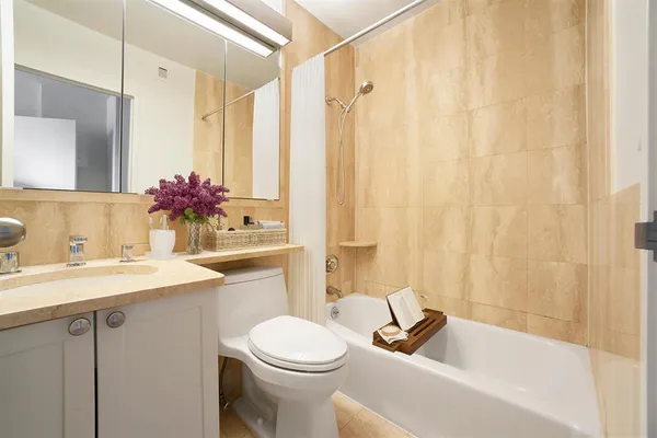 a bathroom with a sink a toilet a mirror a bathtub and shower
