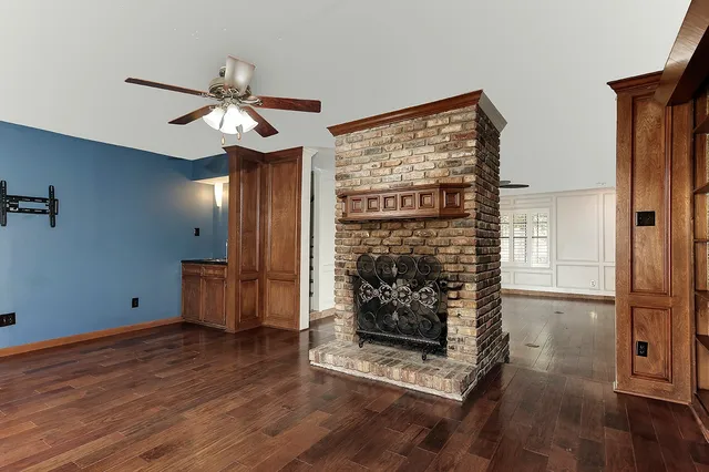 a view of a livingroom with wooden floor a ceiling fan and staircase