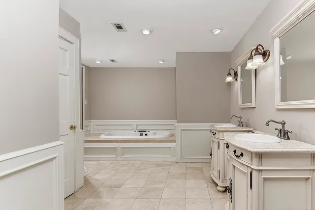 a bathroom with a sink a vanity a mirror and a bathtub