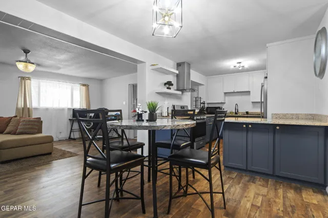a kitchen with stainless steel appliances kitchen island granite countertop a table chairs and a refrigerator