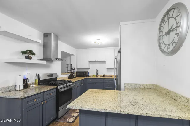 a kitchen with granite countertop a sink a stove and lots of wooden cabinets