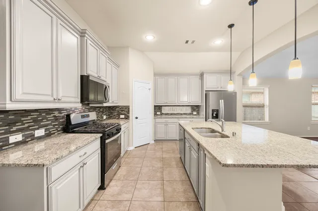 a kitchen with stainless steel appliances granite countertop a sink stove and refrigerator