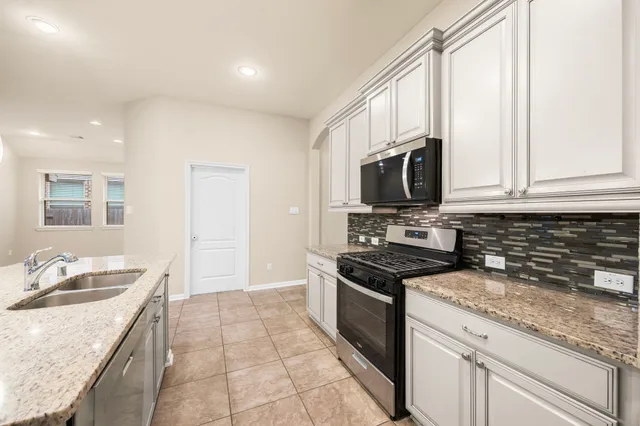 a kitchen with granite countertop a sink stainless steel appliances and white cabinets