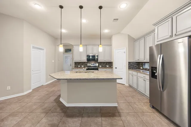 a kitchen with kitchen island a sink stainless steel appliances and a chandelier