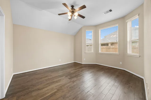 a view of an empty room with window and wooden floor