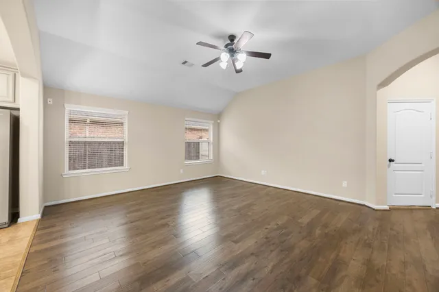 a view of an empty room with wooden floor and a window