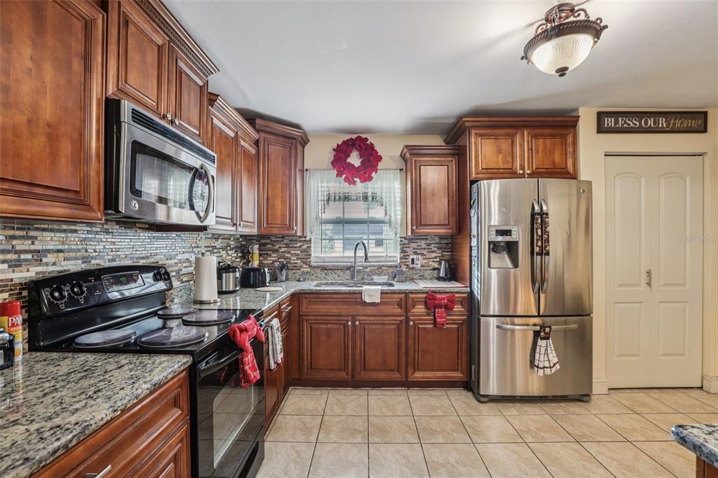 5575 58th Street North Kenneth City, FL 33709 - Photo 8 of 31 a kitchen with stainless steel appliances granite countertop a refrigerator a stove and a sink