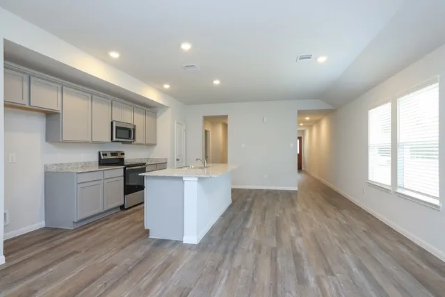 a kitchen with a sink wooden floor stainless steel appliances and cabinets