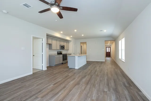 a kitchen with stainless steel appliances kitchen island hardwood floor sink and window
