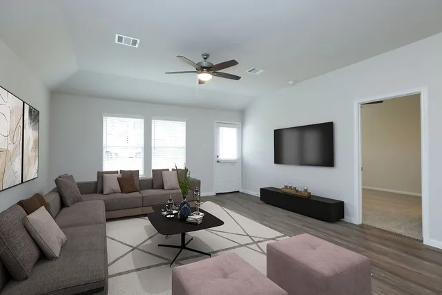 a living room with furniture a flat screen tv and a large window