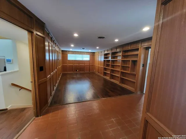 a view of an empty room with wooden floor and stairs