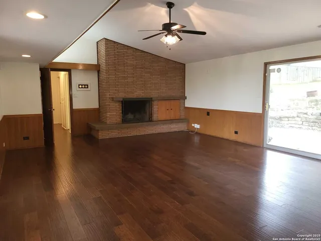 an empty room with wooden floor a fireplace and windows