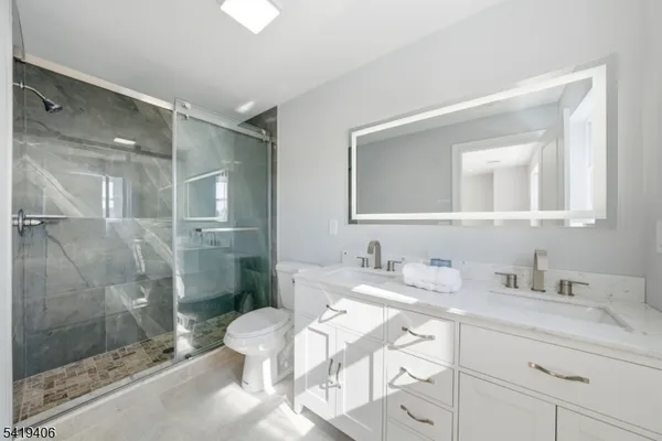 a bathroom with a sink vanity granite toilet and shower