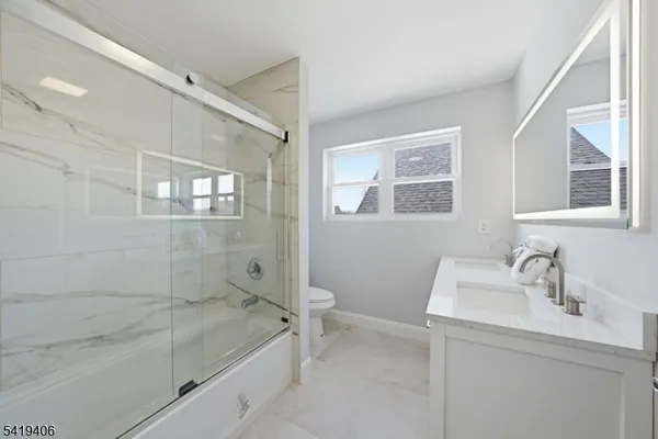 a bathroom with a granite countertop sink a toilet and shower