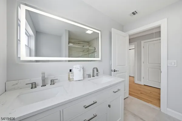 a bathroom with double vanity sink a mirror and a bathtub