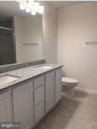 a bathroom with a granite countertop sink a toilet and a mirror