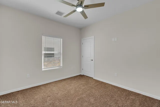 an empty room with a window and a fan