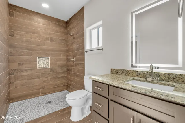 a bathroom with a granite countertop sink a toilet and a mirror