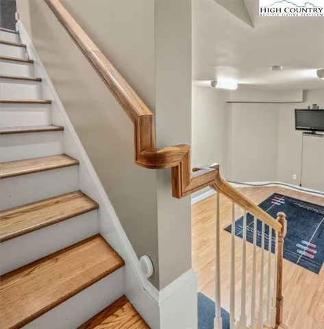 a view of an empty room with stairs and wooden floor