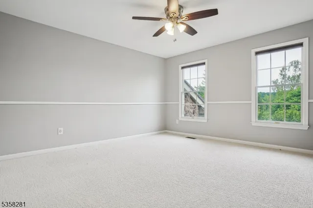 an empty room with windows and chandelier fan
