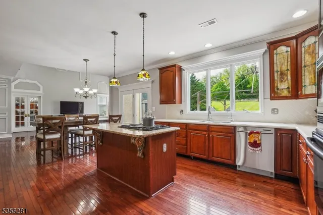 a kitchen with stainless steel appliances granite countertop wooden floors stove sink and wooden cabinets