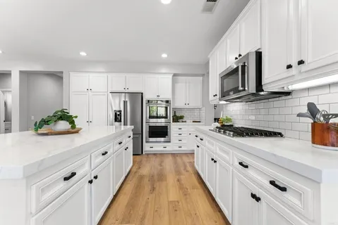 a white kitchen with stainless steel appliances and white cabinets
